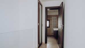 Ein schmaler Korridor mit einer Holztür, die zu einem Badezimmer führt.