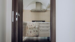 Eine schmale Küche mit Herd, Backofen und einer Pendelleuchte.