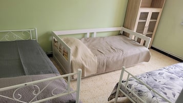 Une chambre avec deux lits simples, une armoire en bois et un mur vert.
