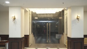 A lobby with a checkered floor, a chandelier, and wall sconces. - Hotel Shringar Mahal  (Vrindavan)