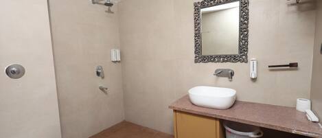 A bathroom with a shower, toilet, sink, and a mirror with an ornate frame.