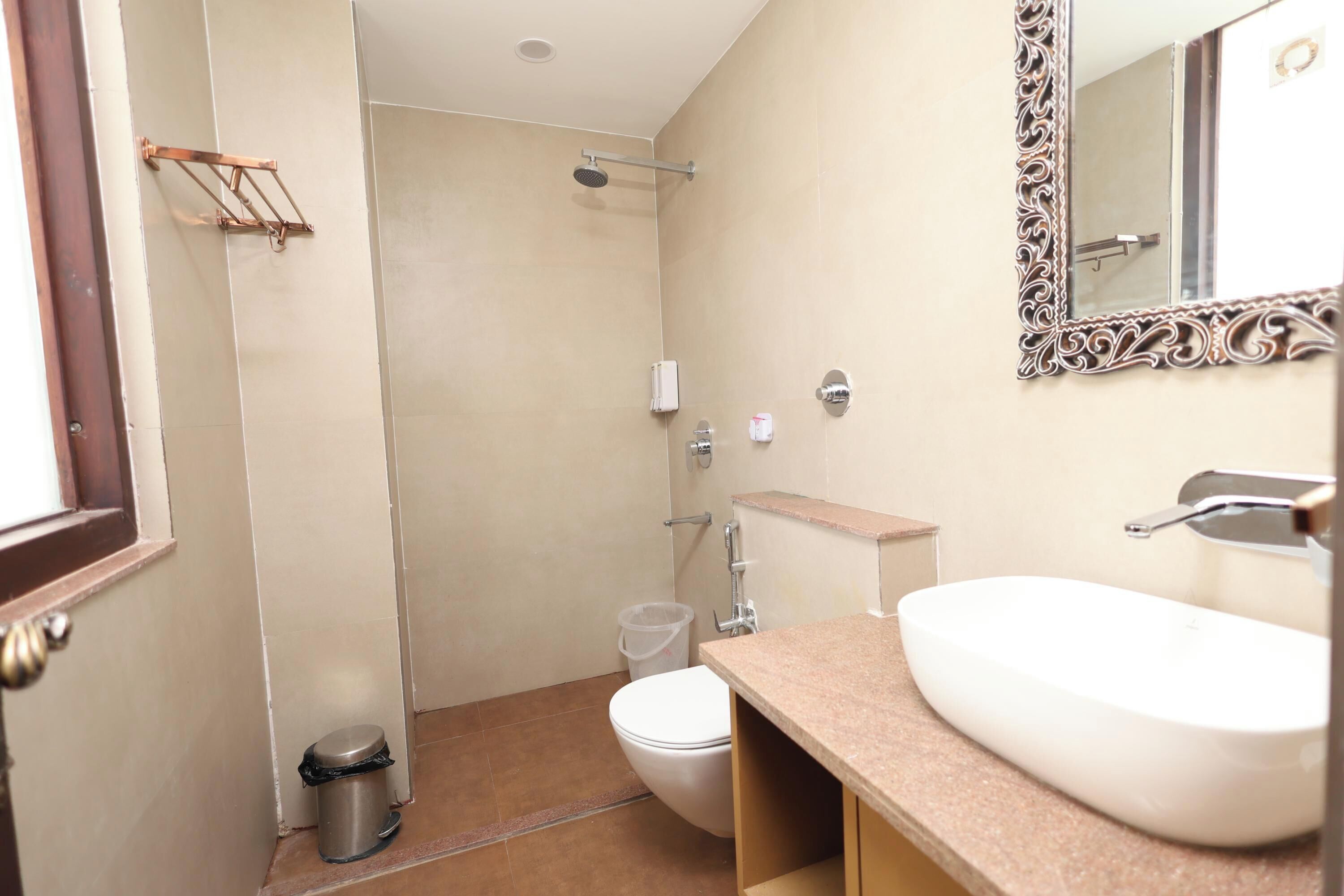 A bathroom with a sink, toilet, shower, and a mirror with an ornate frame.