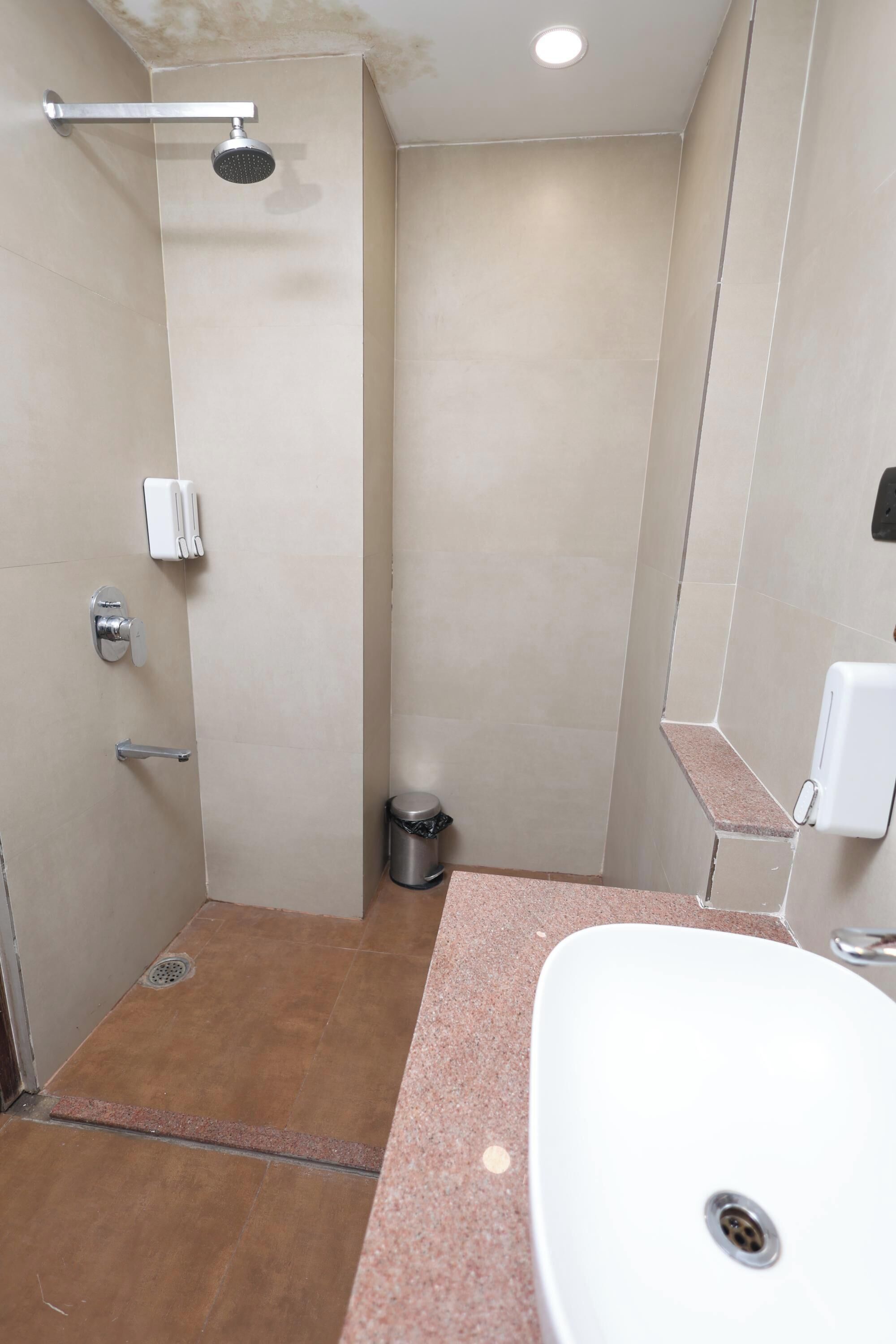Un bagno con doccia, WC, lavandino e cestino.