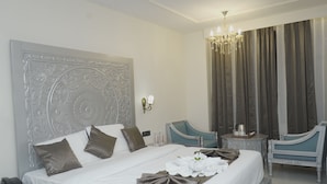 A hotel room with a large bed, a chandelier, a desk, and a chair. - Hotel Shringar Mahal  (Vrindavan)