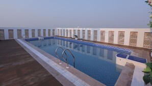 A rooftop pool with clear blue water, metal handrails, and a wooden deck. - Hotel Shringar Mahal  (Vrindavan)