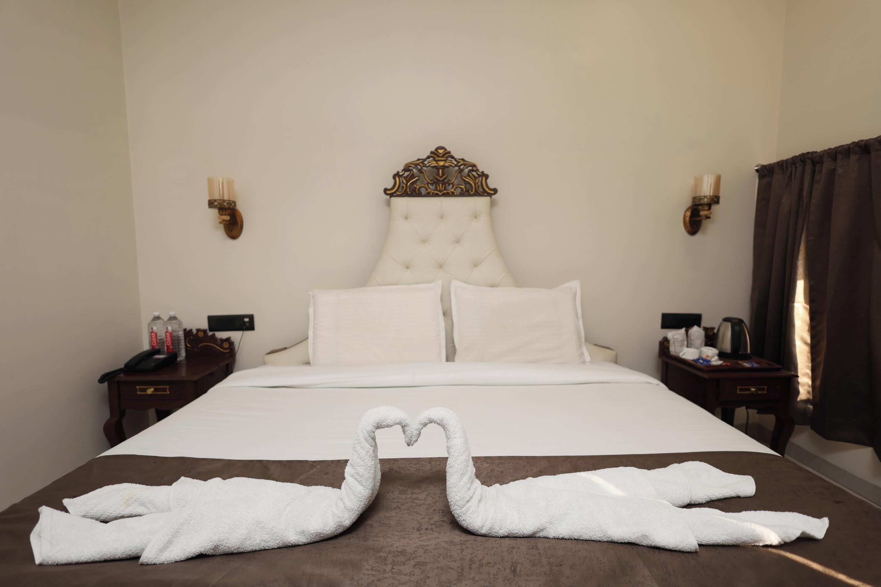 A hotel room with a large bed, two bedside tables, a headboard, and a decorative wall sconce.