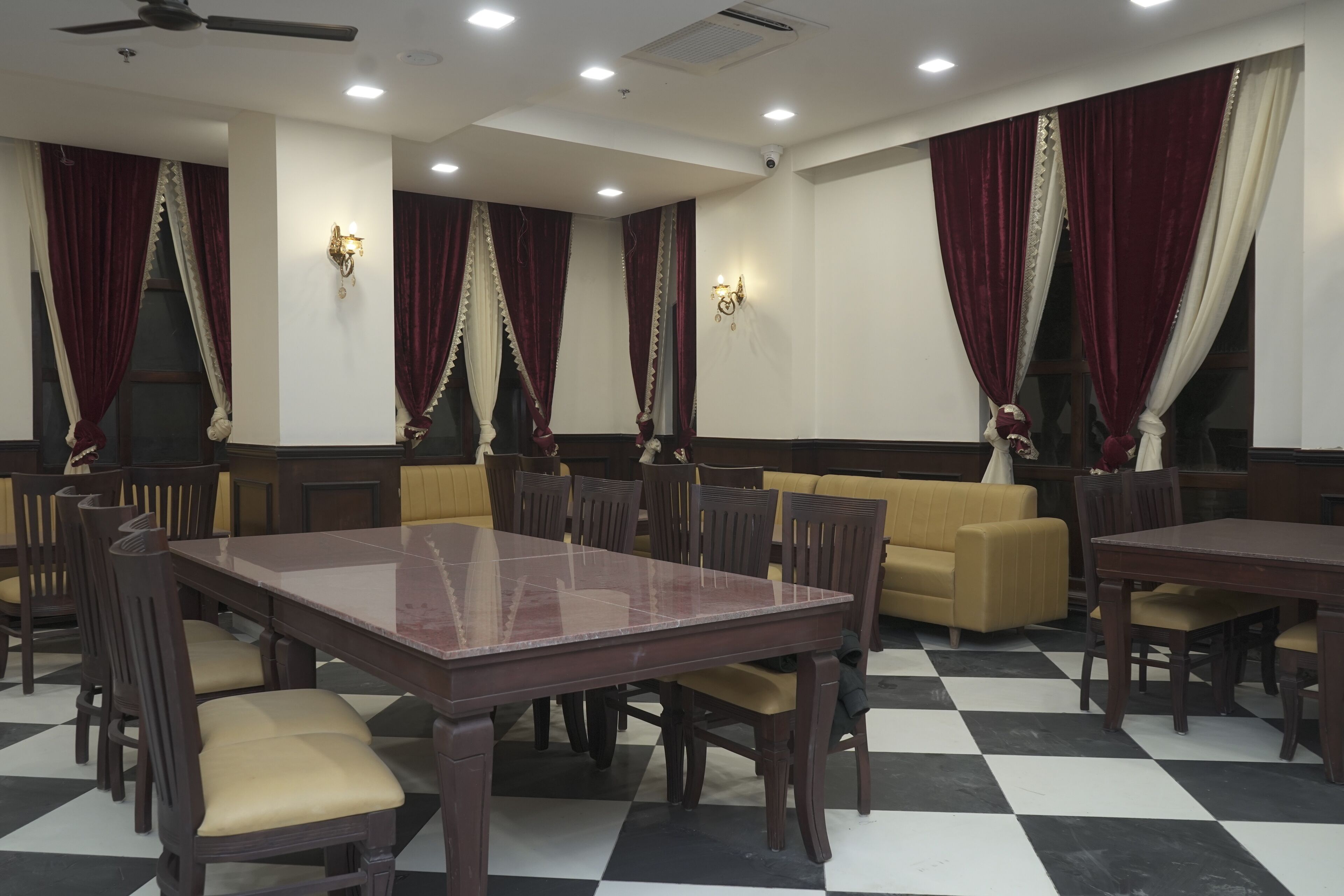 A dining area with a checkered floor, wooden tables, and chairs.