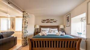 Un dormitorio con una cama de madera, dos mesitas de noche con lámparas, una obra de arte en la pared y una ventana con vistas.