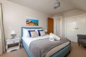 Ein ordentlich eingerichtetes Schlafzimmer mit Bett, Nachttischen, einem Bild und einem Kleiderschrank.