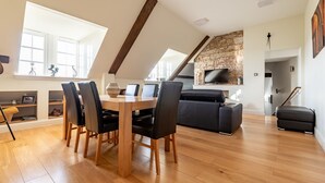 Eine geräumige Loft-Wohnung mit Essbereich, einem Wohnzimmer mit Kamin aus Naturstein und einem großen Fenster für natürliches Licht.