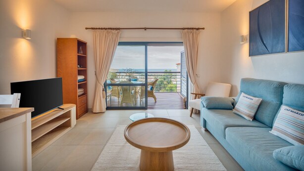 Una sala de estar moderna con televisor, sofá y vistas al exterior.