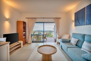 Un salon moderne avec un téléviseur, un canapé et une vue sur l’extérieur.