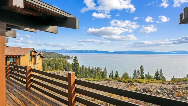 Um deck de madeira com vista para um lago e montanhas.