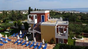 A hotel with a pool, sun loungers, and a view of the sea. - Astra Village (Koutouloufari)