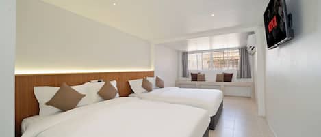 Habitación de hotel con dos camas, un televisor montado en la pared y una ventana con persianas.