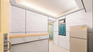 A modern kitchen with marble walls, a built-in oven, and a refrigerator. - Joy Hella Inn (Kowloon)