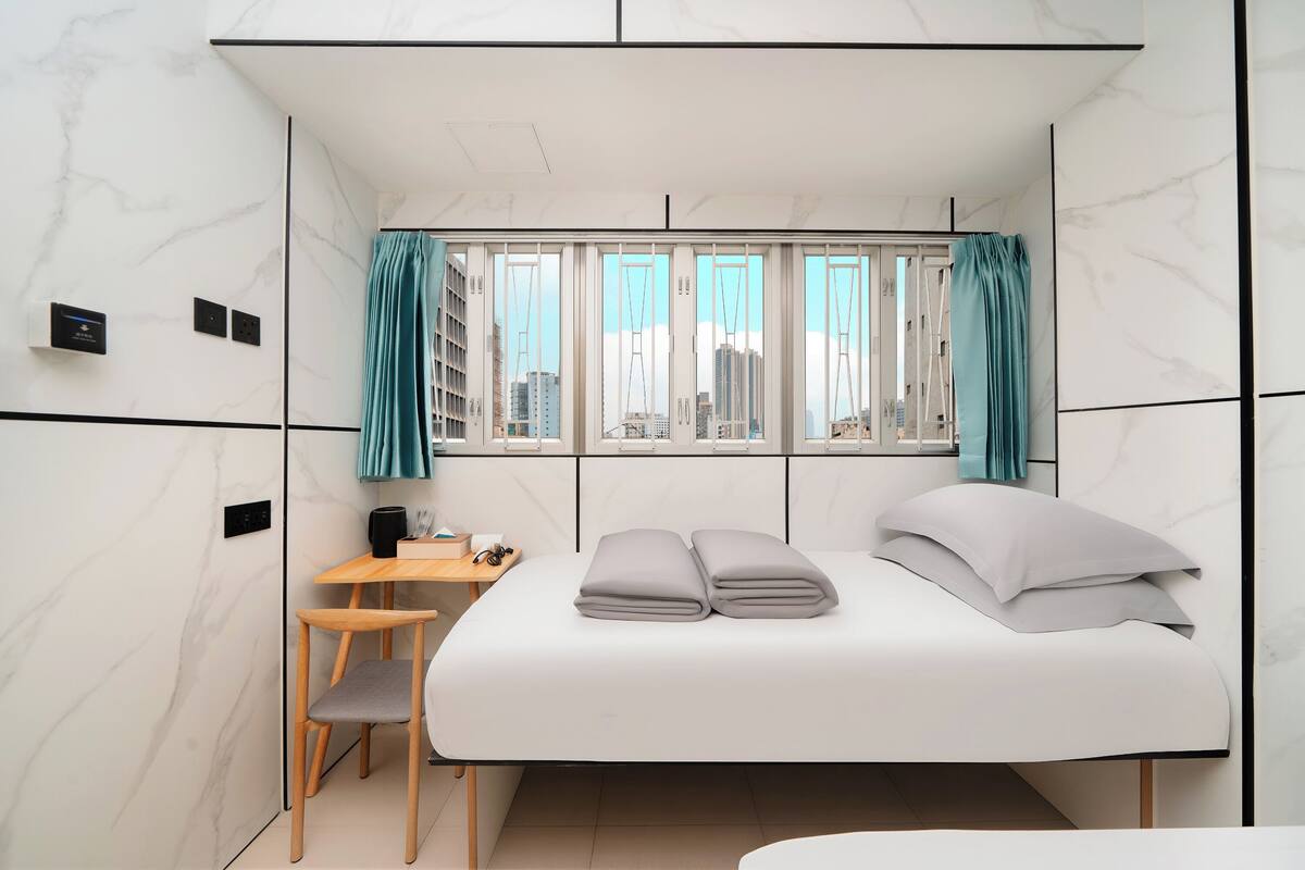 Une chambre d’hôtel moderne, équipée d’un lit, d’un bureau et d’une chaise.