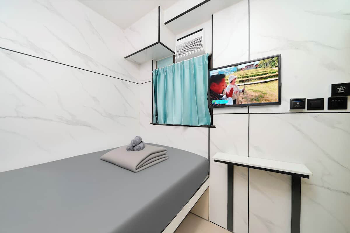 Une chambre moderne équipée d’un lit, d’un téléviseur fixé au mur et d’un petit meuble.