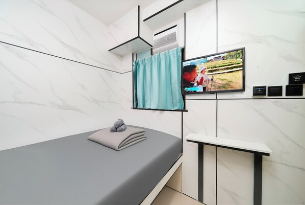 A modern room with a bed, a TV mounted on the wall, and a small cabinet. - Joy Hella Inn (Kowloon)
