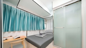 A compact bedroom with a bed, a desk, and a wardrobe. - Joy Hella Inn (Kowloon)