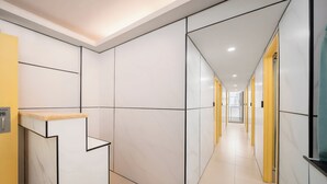 A modern hallway with white walls, black lines, and a wooden reception desk. - Joy Hella Inn (Kowloon)