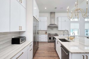 A modern kitchen with white cabinetry, a built-in oven, and a stainless steel range hood. - Gulf Views, Pvt Pool, Golf Cart, Steps To Beach! (Santa Rosa Beach)