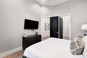 A bedroom with a bed, a dresser, a television mounted on the wall, and a door leading to another room. - Gulf Views, Pvt Pool, Golf Cart, Steps To Beach! (Santa Rosa Beach)