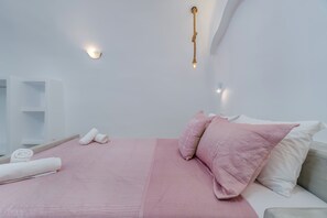 Ein modernes Schlafzimmer mit Bett, Kissen, einem Handtuch und einer Wandleuchte.