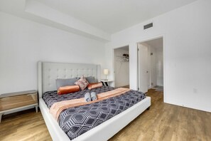 A modern bedroom with a large bed, a bedside table, and a walk-in closet. - Stylish 2BR Deluxe Family Apartment by Dtla (Los Angeles)
