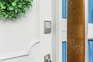 A white door with a keypad lock, a green plant, and a textured glass panel. - Near Light Rail, 5 Mi to Lumen Field: Seattle Base (Seattle)