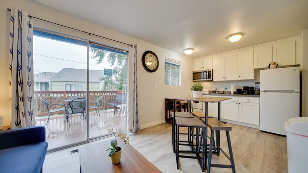 Una cocina moderna con armarios blancos, una mesa de comedor de madera y un amplio ventanal corredizo que da a un patio exterior.