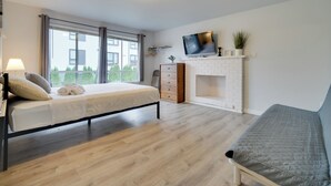 Un dormitorio con cama, televisión, chimenea y ventana.