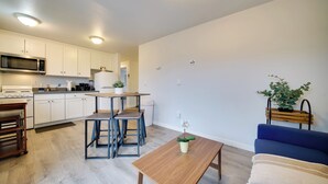Una cocina moderna con armarios blancos, un microondas y una zona de comedor con una mesa y sillas.
