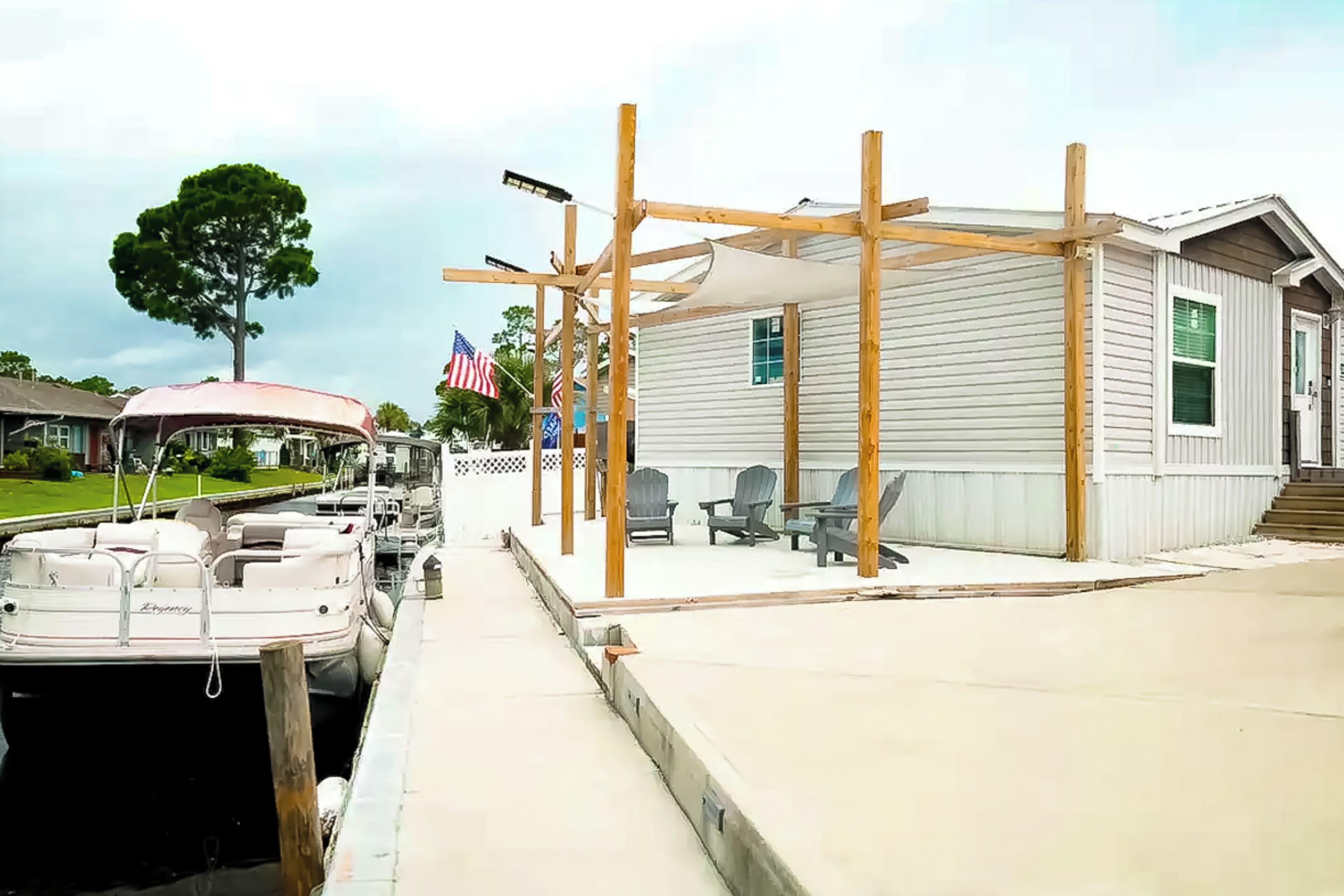 Un quai avec des bateaux, un espace de repos couvert et une maison avec une véranda.