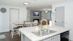 A modern kitchen with a marble countertop, stainless steel sink, and white cabinetry. - 3BR Canal-front Home w/ Wifi & Boat Dock (Panama City Beach)