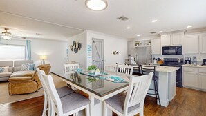 A modern kitchen with white cabinets, a stainless steel refrigerator, and a black microwave. - 3BR Canal-front Home w/ Wifi & Boat Dock (Panama City Beach)