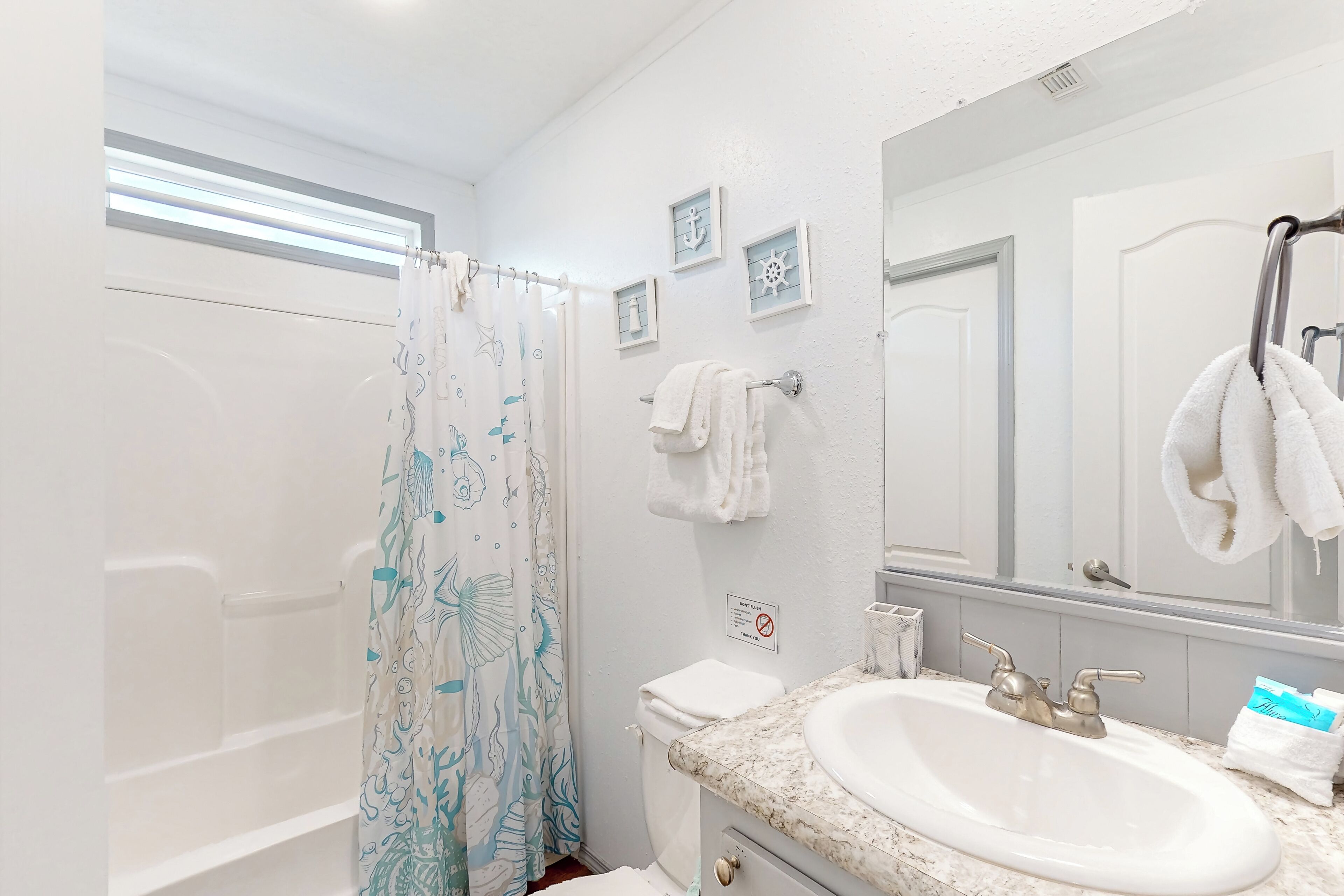 Un baño con cortina de ducha, inodoro, lavabo y espejo.