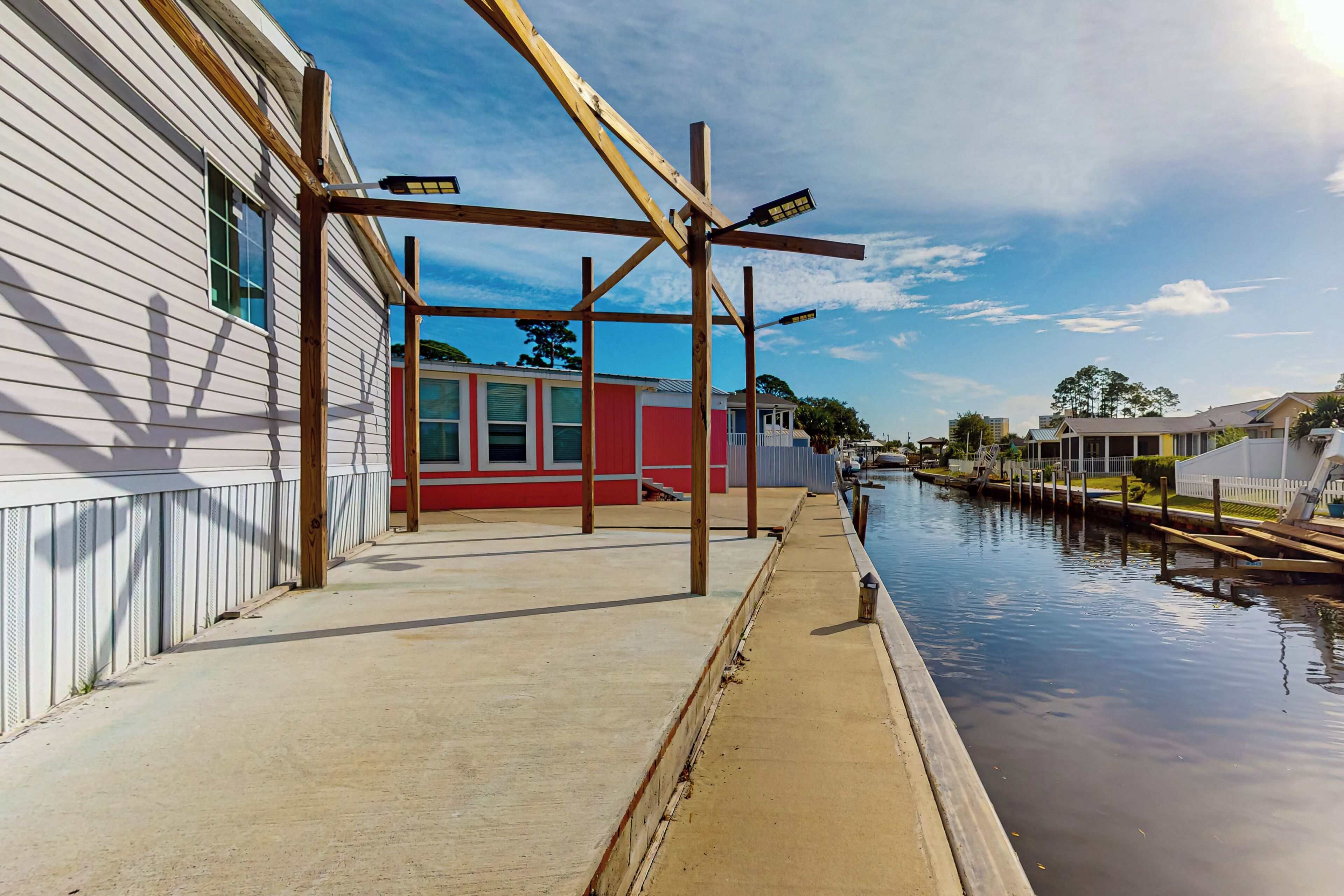 Propiedad frente al agua con muelle de madera, un edificio rojo y un canal.