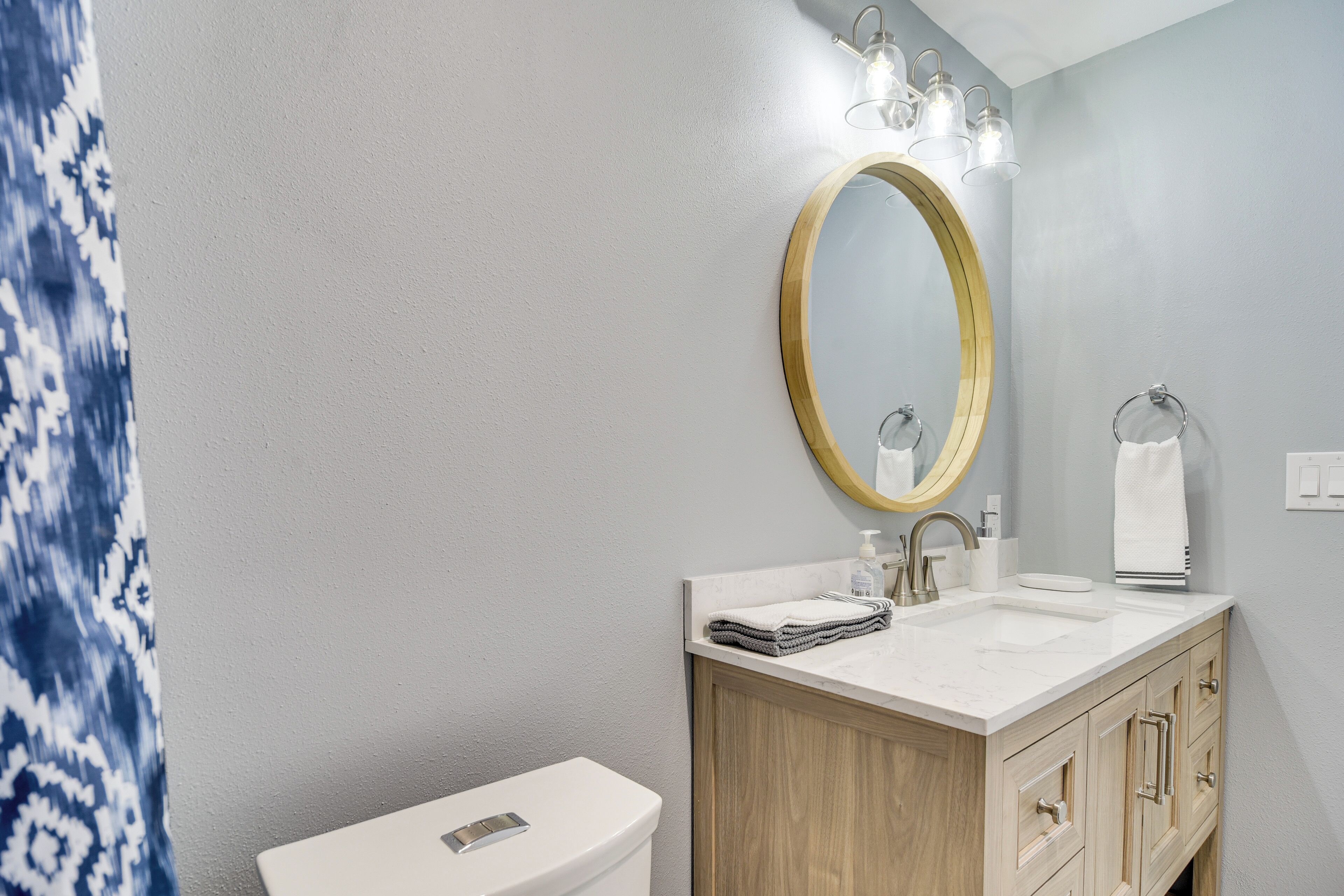 Une salle de bain comprenant des toilettes, un lavabo, un meuble-lavabo en bois et un grand miroir avec éclairage.