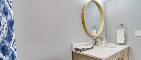 Une salle de bain comprenant des toilettes, un lavabo, un meuble-lavabo en bois et un grand miroir avec éclairage.
