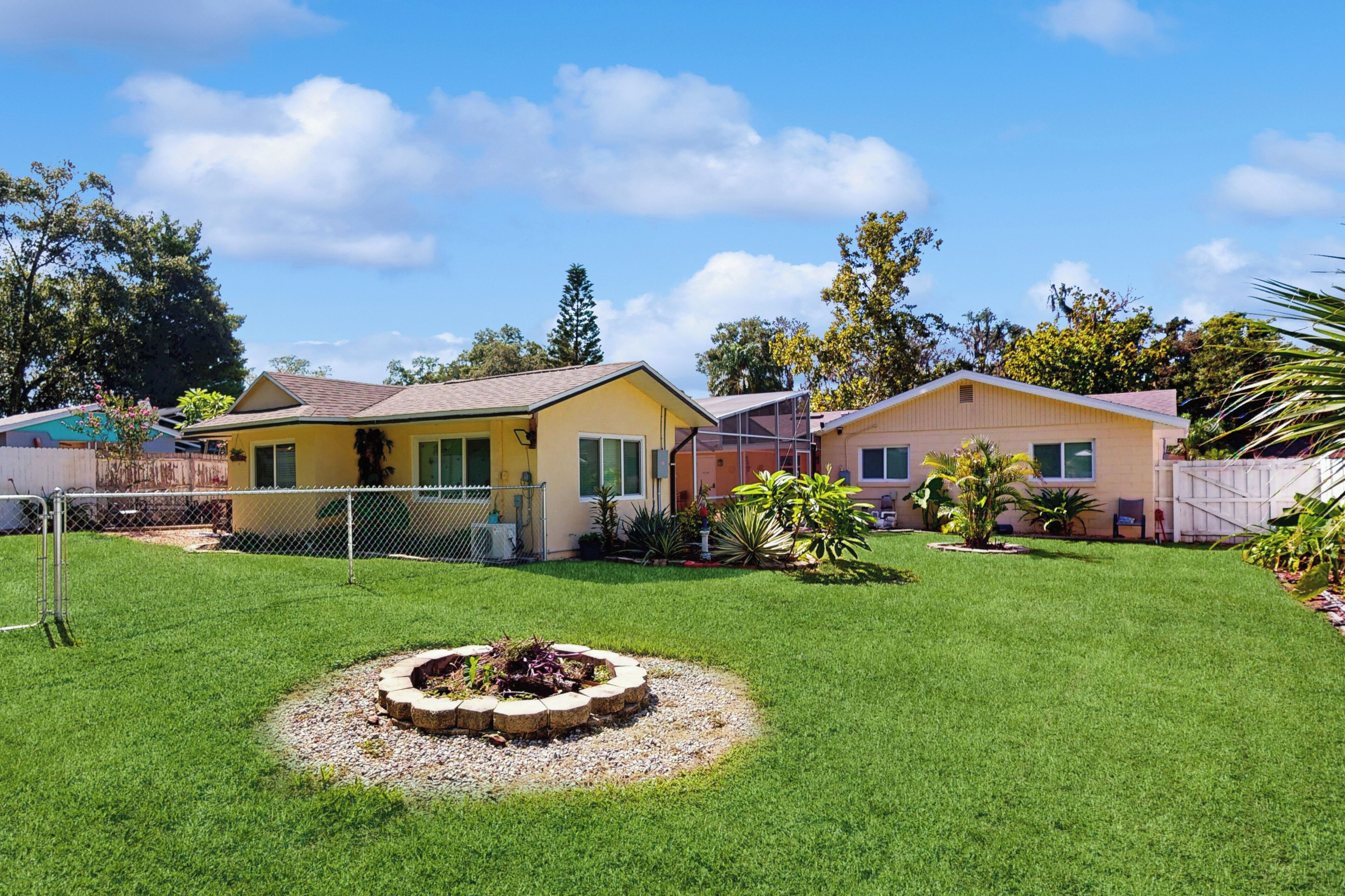 Zona residencial con dos casas, césped cuidado y un jardín circular.