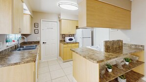 A modern kitchen with granite countertops, wooden cabinets, and a built-in microwave. - Pool Access! Dog-friendly Retreat 16 Mi to Orlando (Longwood)