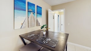 A dining area with a wooden table, three framed beach paintings, and a potted plant. - Pool Access! Dog-friendly Retreat 16 Mi to Orlando (Longwood)