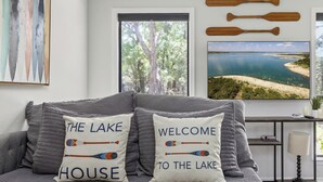 A bedroom with a bed, pillows, a painting, a window, and a view of a lake. - Lakefront, Private 3br, Dog-friendly Rental (Canyon Lake)