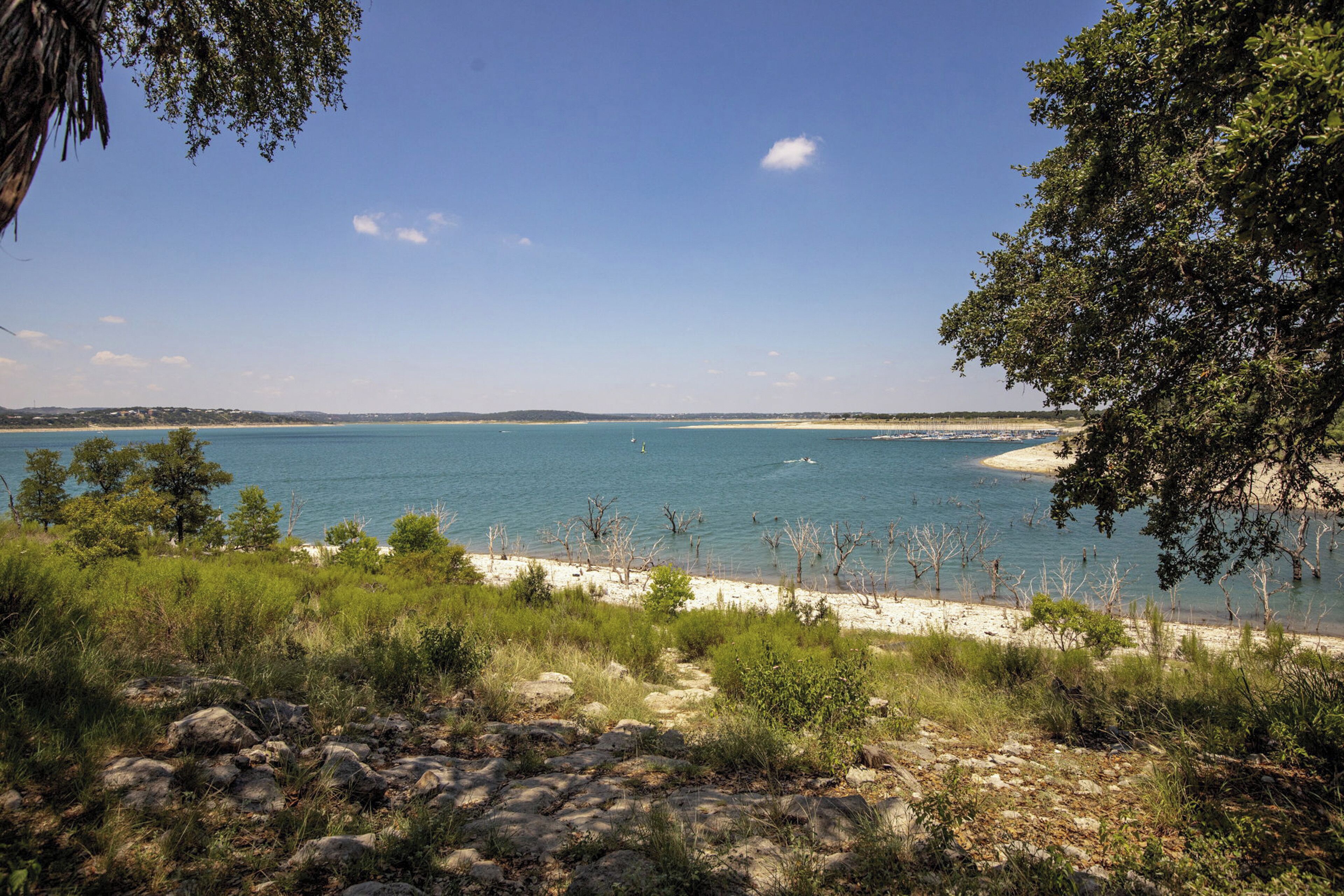 A coastal landscape with a clear view of the sea, sandy beach, and surrounding vegetation.