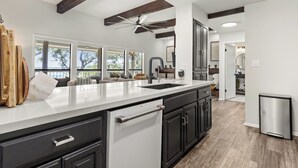 A modern kitchen with a large island, dark cabinetry, and a view of the outdoors. - Lakefront, Private 3br, Dog-friendly Rental (Canyon Lake)