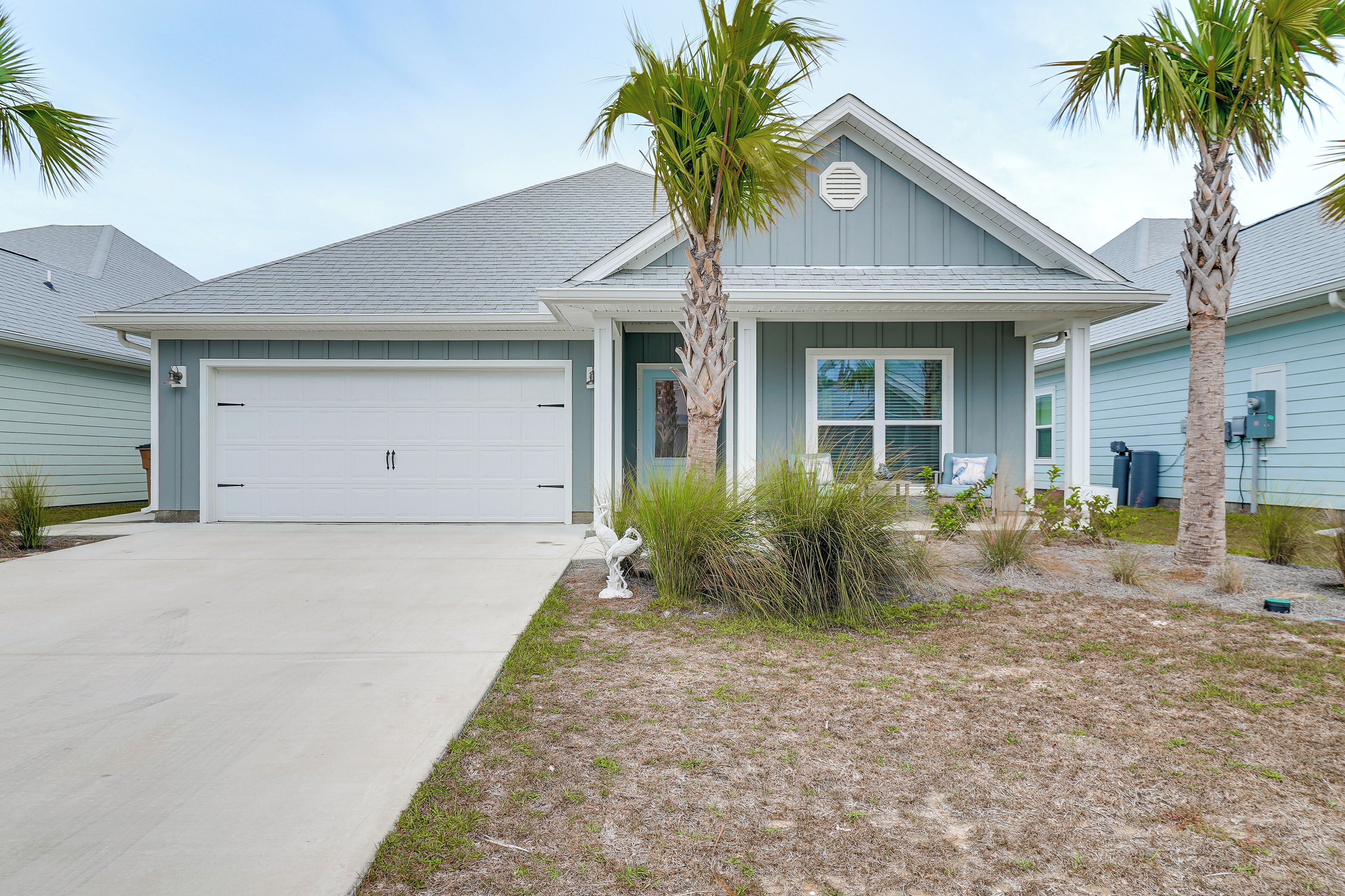 A residential house with a garage, palm trees, and a well-maintained lawn.