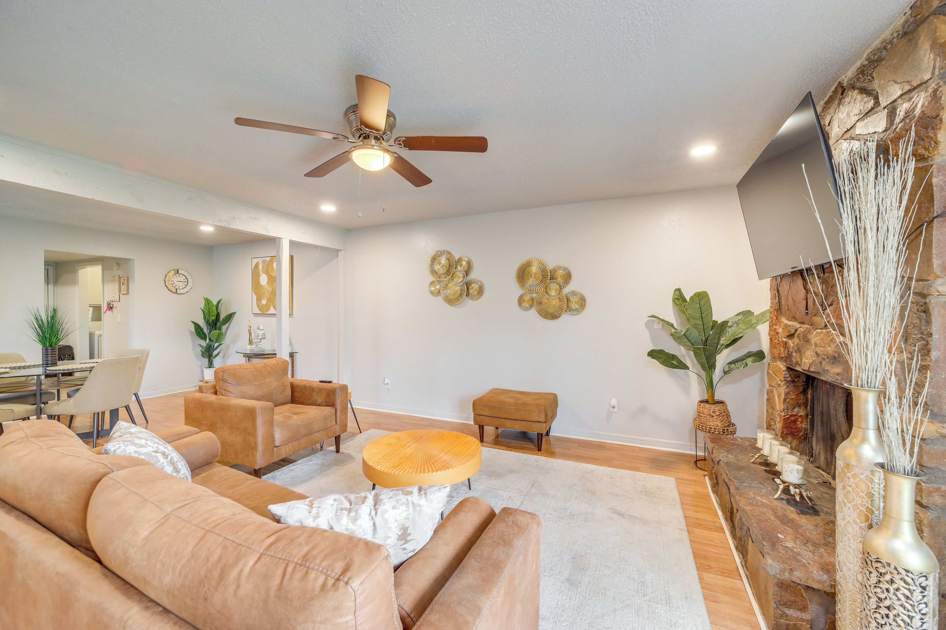 A spacious living room with a large sofa, a round coffee table, and a fireplace with decorative items.
