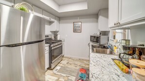 A modern kitchen with stainless steel appliances, white cabinetry, and a marble countertop. - Pet-friendly Retreat w/ Yard, 12 Mi to Dtwn Tulsa (Tulsa)
