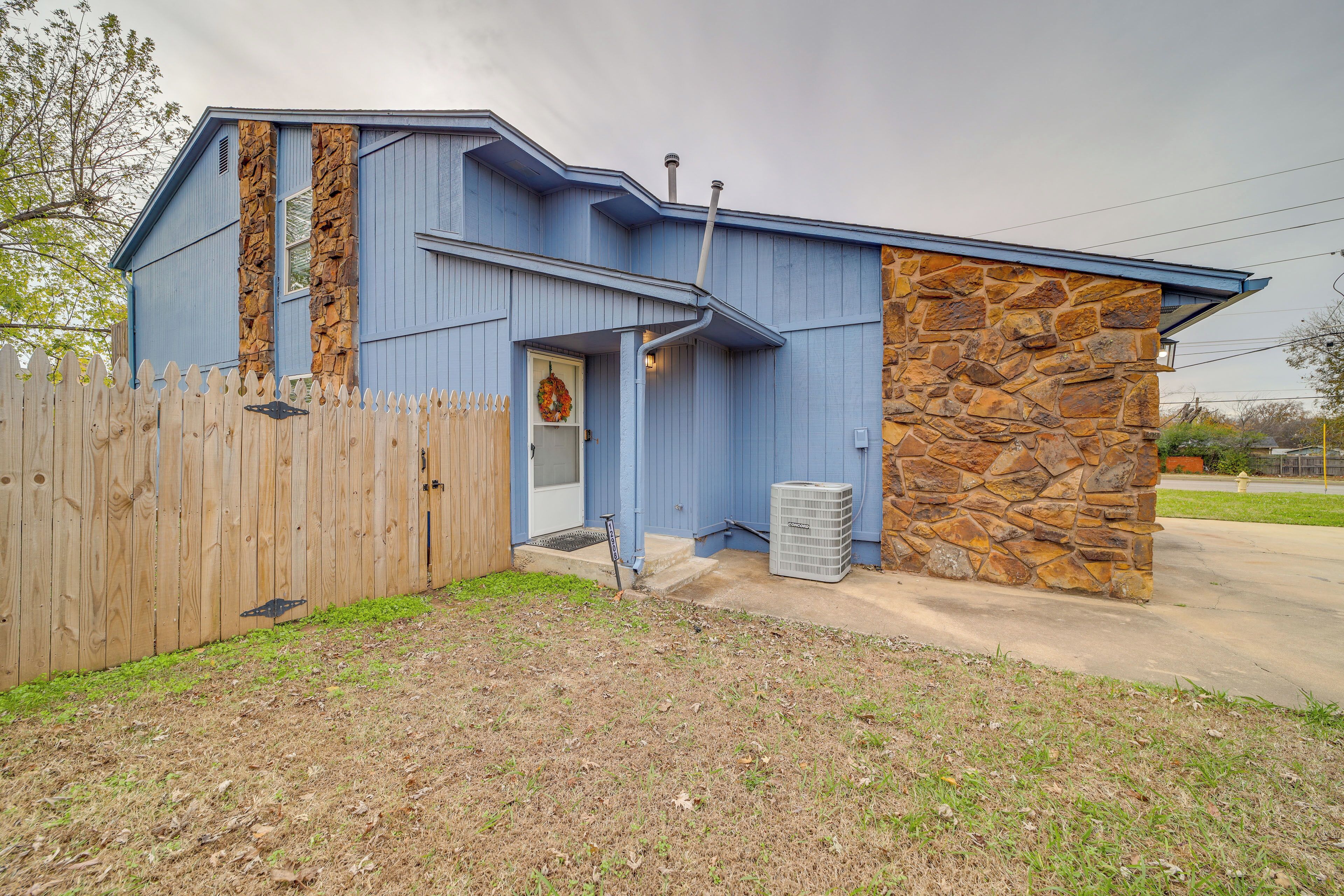 A building with a blue exterior, a stone accent wall, and a wooden fence.